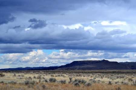 Gray Grass Field Leading To Mountains Under Gray Heavy Clouds photo