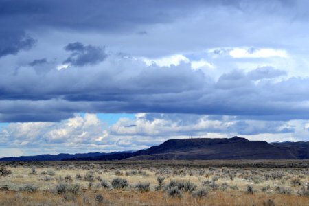 Gray Grass Field Leading To Mountains Under Gray Heavy Clouds