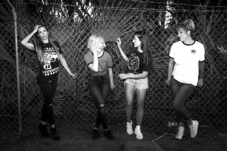 Grayscape Photo Of Four Women Near Cyclone Wire Fence