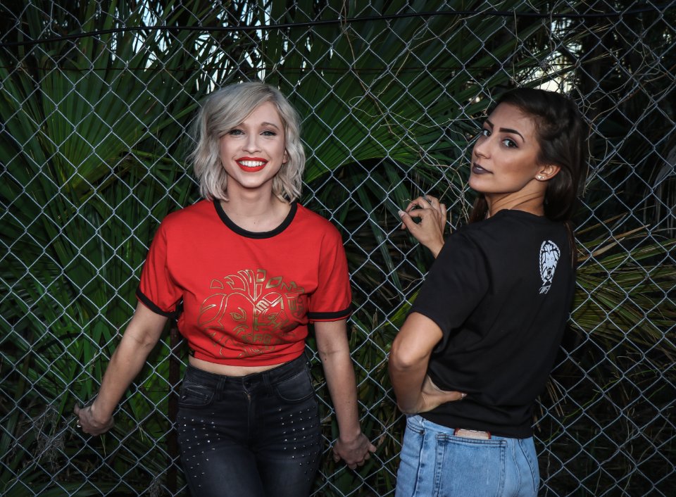 Two Woman In Black And Red Dress Standing Near Fence