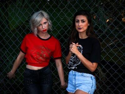 Two Woman Leaning On Fence