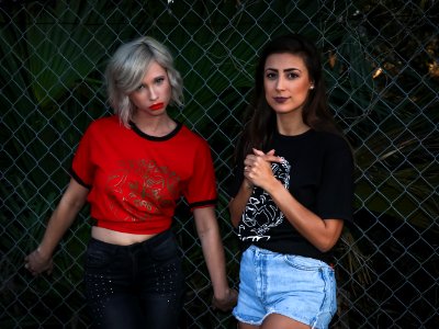 Two Woman Leaning On Fence