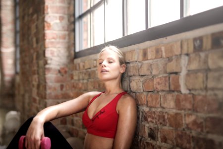 Woman In Red Brassier Leaning On Brown Brick Wall