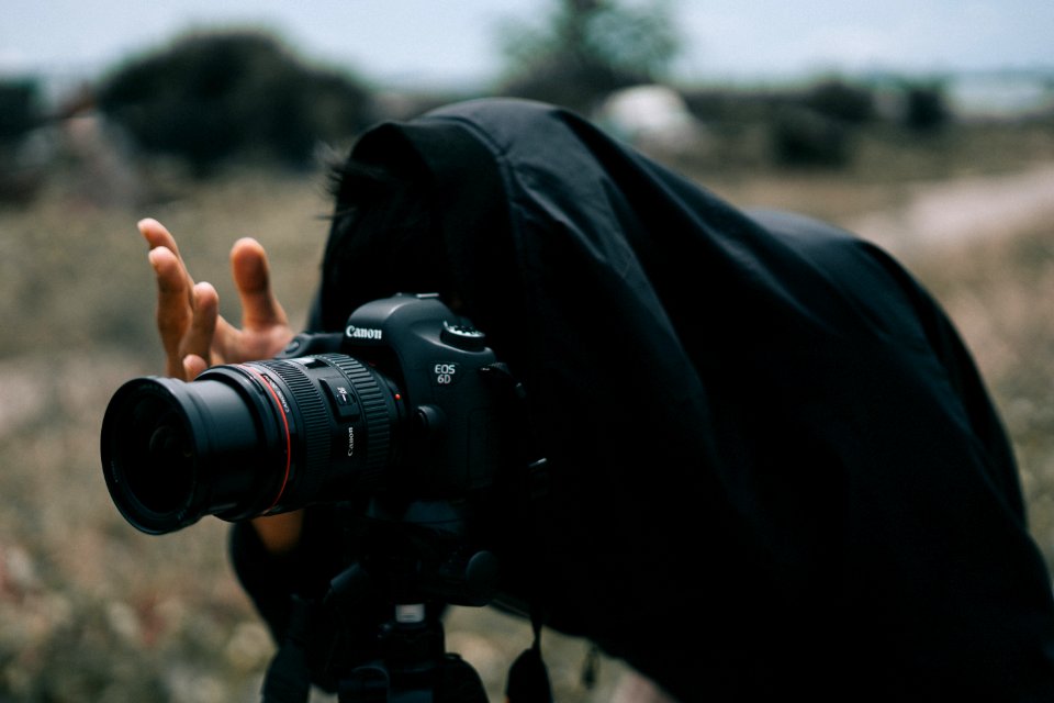 Person In Black Jacket Facing Black Canon Dslr Camera
