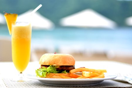 Burger With Lettuce And Fries On Plate Beside Pineapple Juice