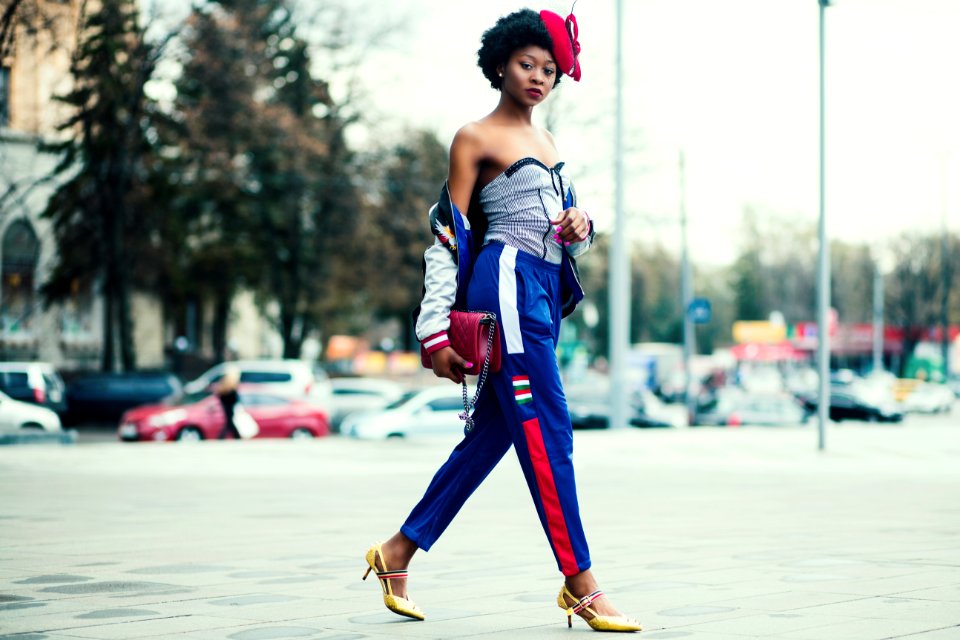 Woman Wearing White Sweetheart Neckline Shirt With Blue And Red Pants Walking Across The Street