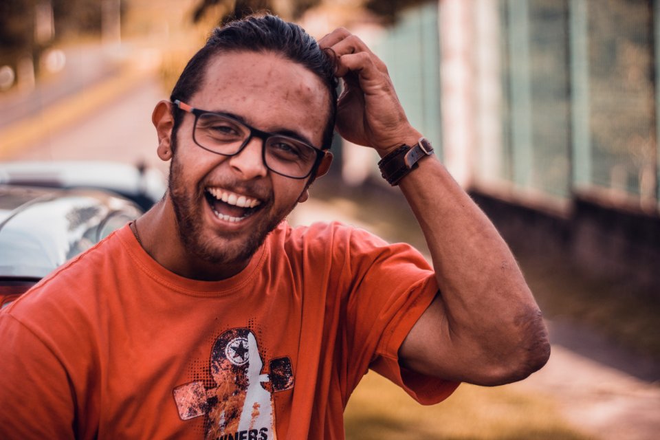Selective Focus Photography Of Man Smiling Putting Hands On Head