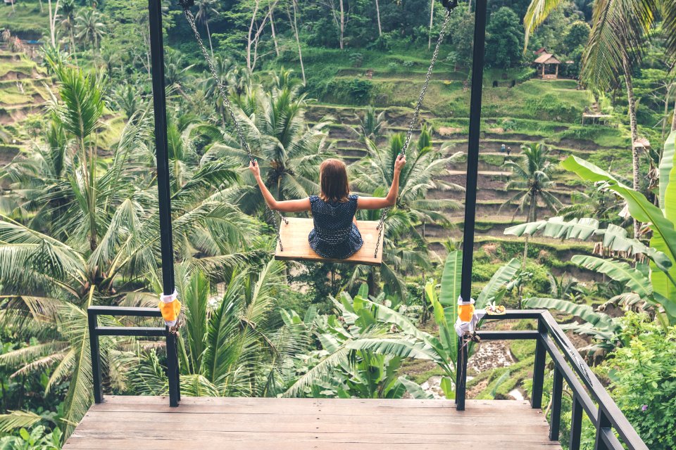 Girl Swinging Above Green Trees At Daytime photo