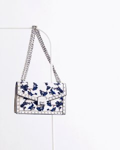 White And Blue Floral Flap Sling Bag Hanging On White Steel Rack photo