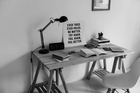 Grayscale Photography Of Desk With Books And Table Lamp photo