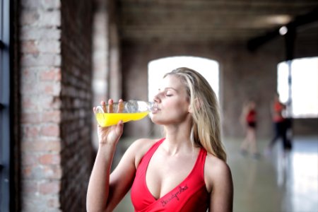 Selective Focus Photography Of Woman In Red Tank Top Drinking photo