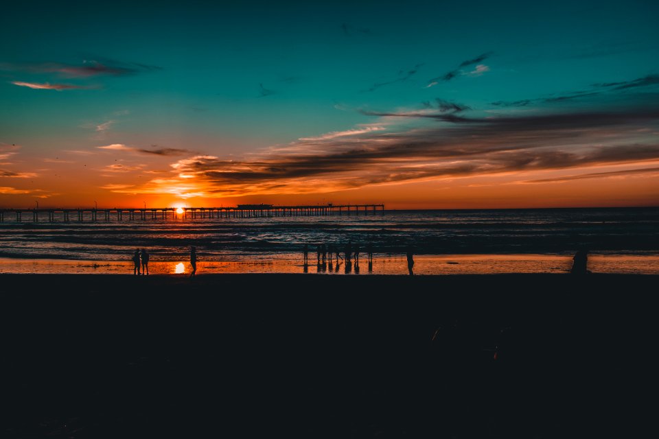 Silhouette Of People Near Body Of Water At Golden Hour