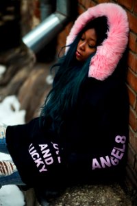 Woman Wearing Black And Pink Coat Leaning On Wall photo