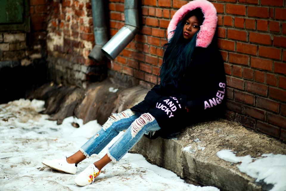 Woman Wearing Black And Pink Parka Leaning On Brown Brick Wall photo