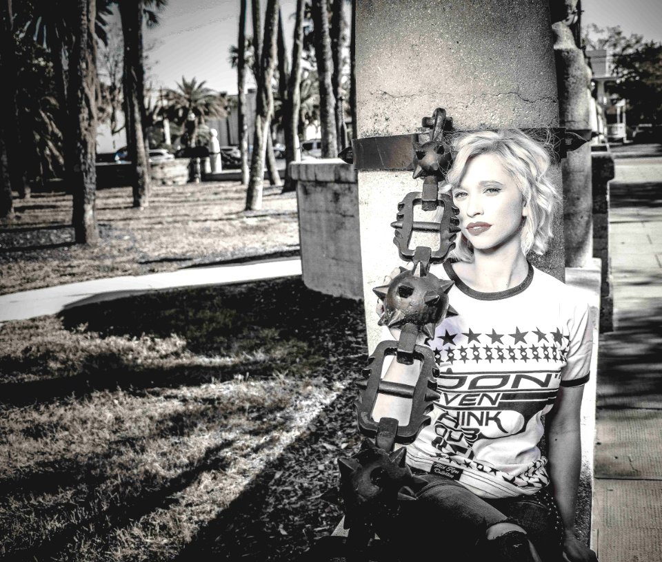 Woman Sitting Beside Gray Concrete Post Grayscale Photo