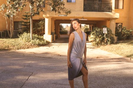 Woman In Gray Deep V-neck Sleeveless Tulip Dress Standing On Gray Floor photo