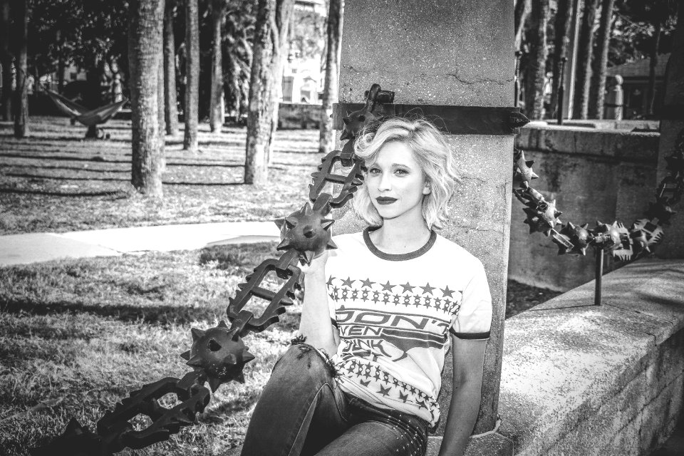 Grayscale Photo Of Woman Sitting On Concrete Wall photo