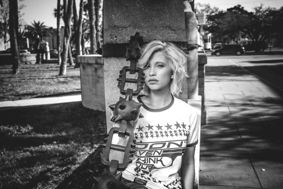 Female Leaning On Gray Concrete Post Grayscale Photo