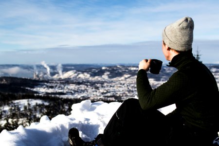 Man Wearing Jacket And Holding Cup Sitting On The Snow photo
