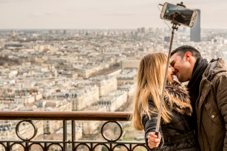 Man Kissing Woman Holding Selfie Stick photo