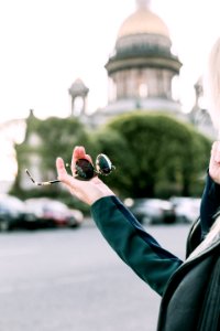 Selective Focus Photography Of Person Holding Black Round Sunglasses