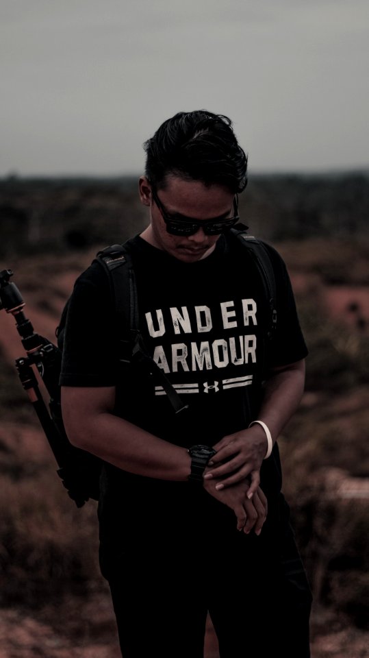 Man Wearing Black And White Under Armour Shirt And Holding His Watch