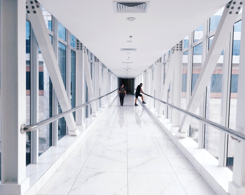 Two People Standing On Hallway Near Glass Window photo