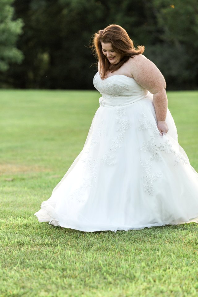 Woman In White Floral Wedding Gown Walks On Green Grass Lawn Yard