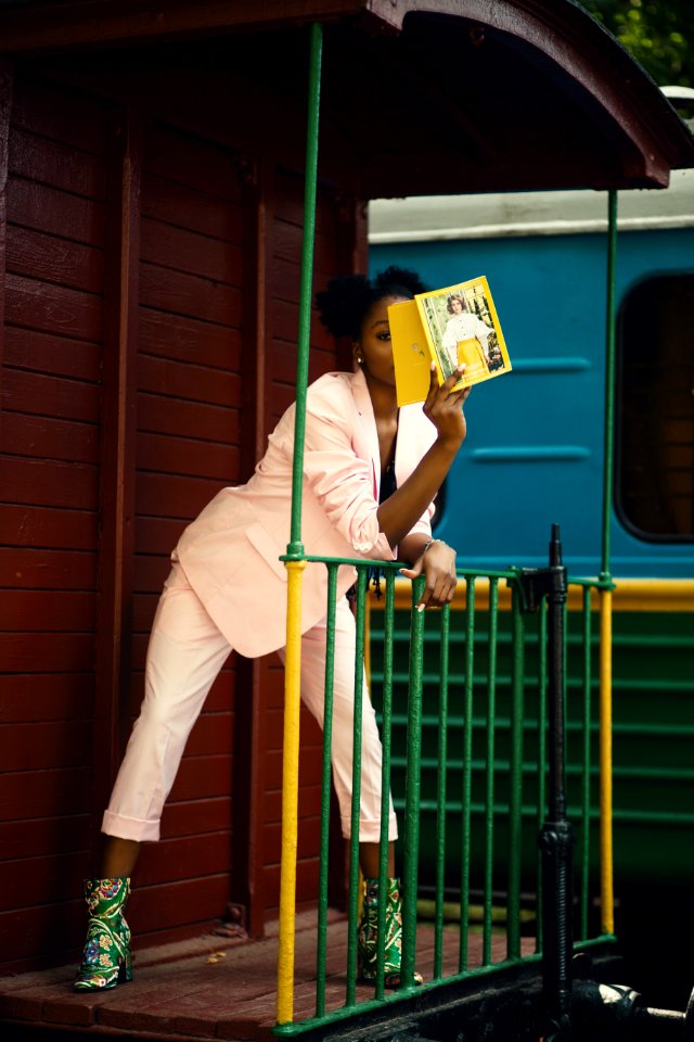 Woman In Pink Suit Coat Leaning On Green Steel Fence photo