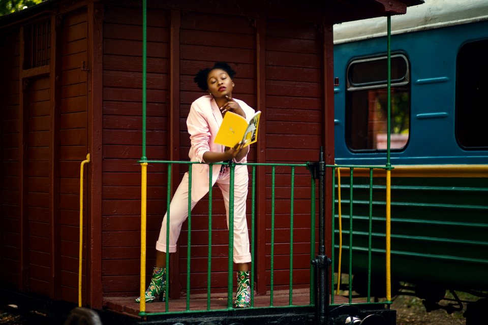 Woman Wearing Pink Blazer Pants And Green Heeled Shoes Holding Yellow Covered Book photo