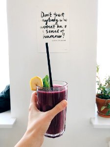 Person Holding Clear Drinking Glass With Purple Smoothie With Quotation Decor photo