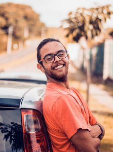 Man In Orange T-shirt Leaning On A Car photo