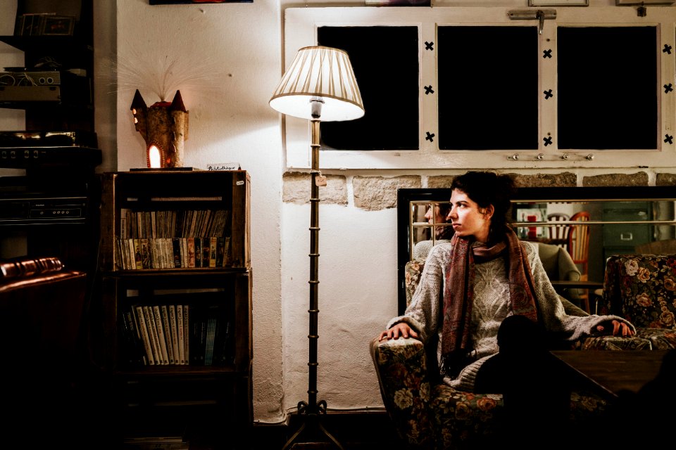 Woman Sitting On Sofa Chair Beside Floor Lamp Leaning On Side