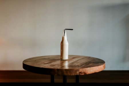 Glass Bottle Filled With Black Straw On Brown Wooden Table photo