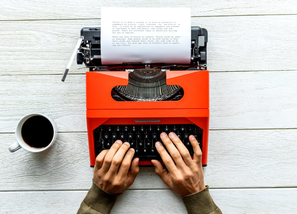 Person Holding Black And Orange Typewriter