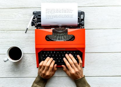 Person Holding Black And Orange Typewriter photo