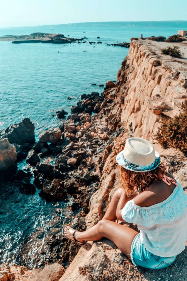 Woman Sitting In Stone Near Body Of Water