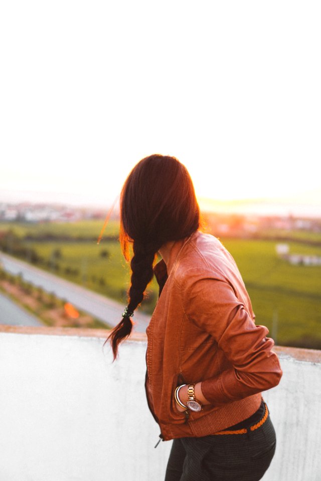 Woman Wearing Brown Leather Jacket Standing And Looking On Grass Field View At Day Time photo