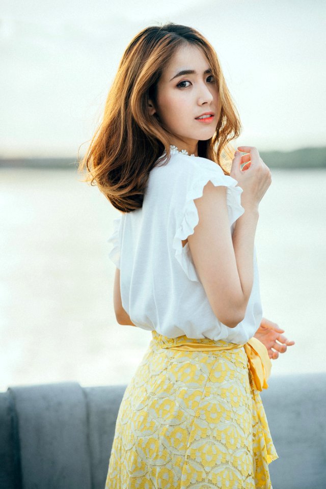 Photo Of Woman Wearing White Sleeveless Shirt And Yellow Floral Skirt Near Body Of Water