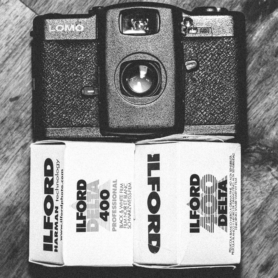 Black Lomo Compact Camera Beside Ilford Delta 400 Black amp White Film Box