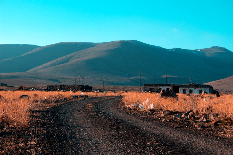 Gray Road In Between Brown Grass Field With Mountains Background