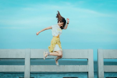 Jumpshot Photography Of Woman In White And Yellow Dress Near Body Of Water photo