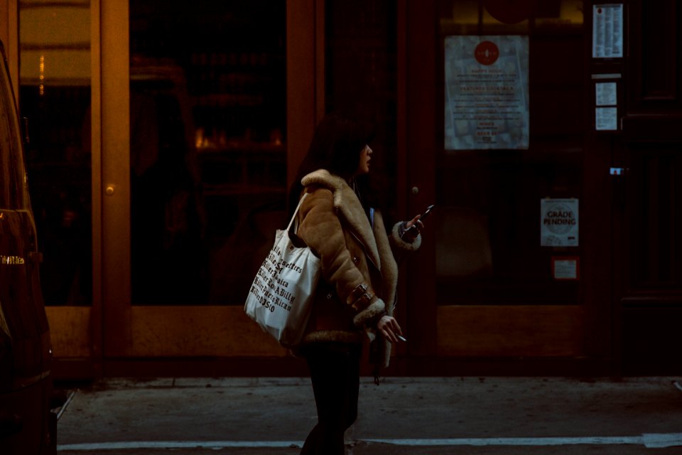 Woman Carrying White Tote Standing Beside Brown Glass Door Building