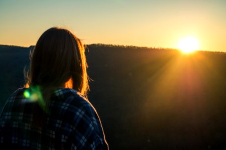 Woman Wearing Plaid Shirt Facing Sun During Golden Hour