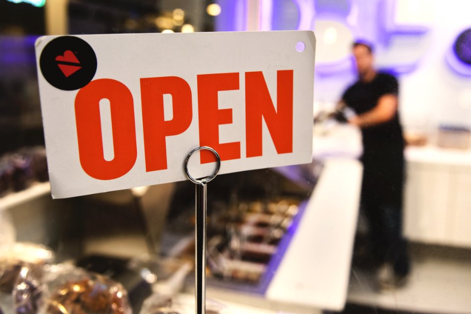Shallow Focus Photography Of Red And White Open Signage Near Man Wearing Black Shirt
