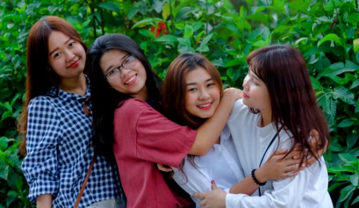 Four Women Wearing Shirts Standing Beside Green Leaf Plants photo