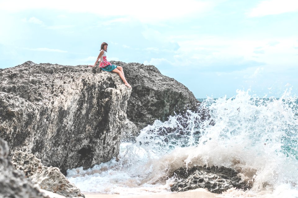 Woman Sitting Of Rock Near Body Of Water