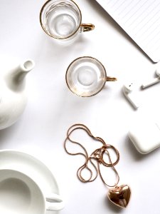 Gold-colored Heart Pendant Necklace Beside Two Glass Mugs On Table