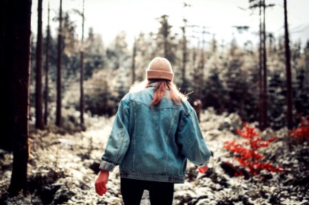 Woman Wearing Blue Denim Jacket And White Beanie Walking In The Forest photo