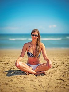 Woman Wearing White-and-black Bikini Sitting On Sand Near Seashore